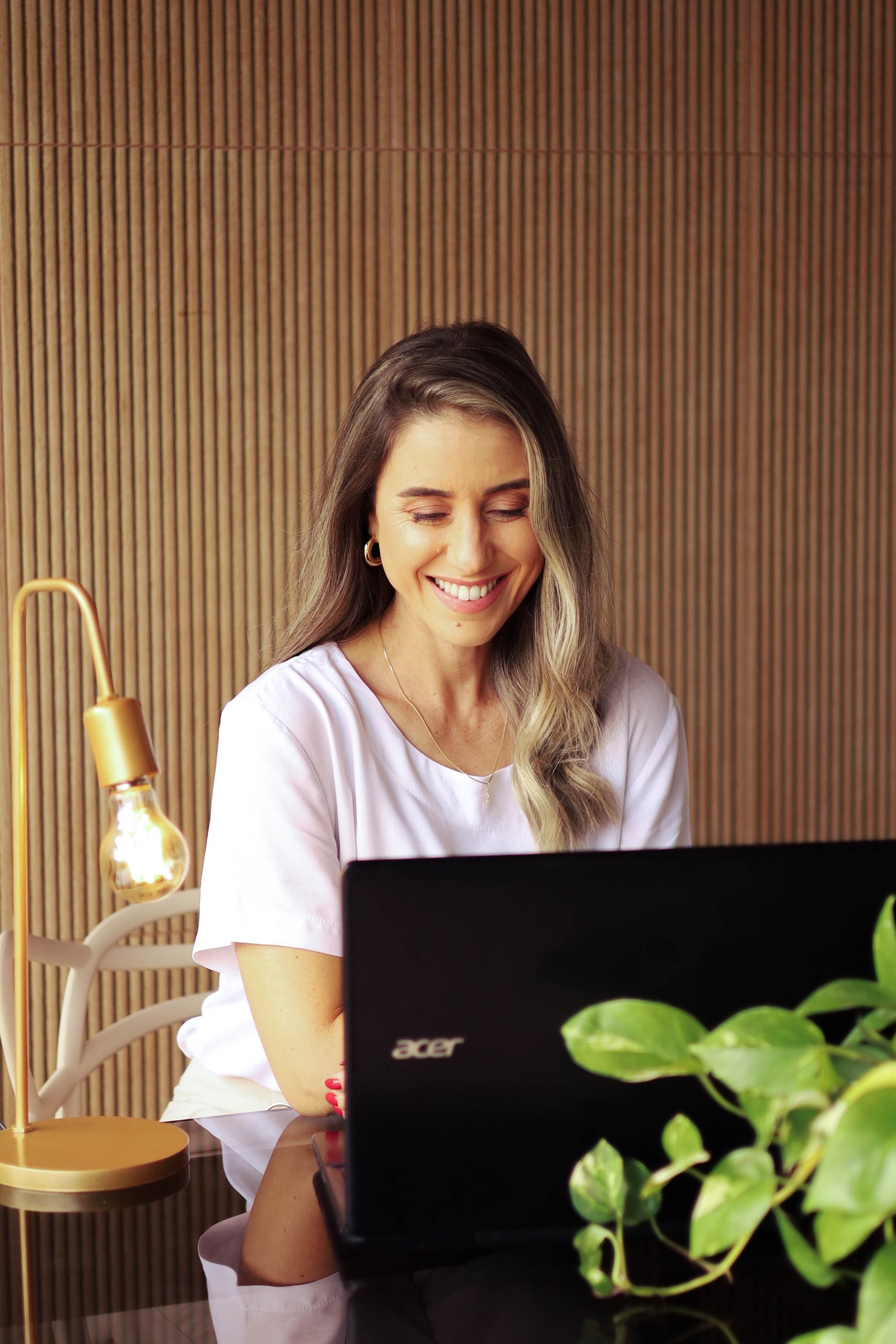 Pâmela no notebook, sorrindo de forma leve.